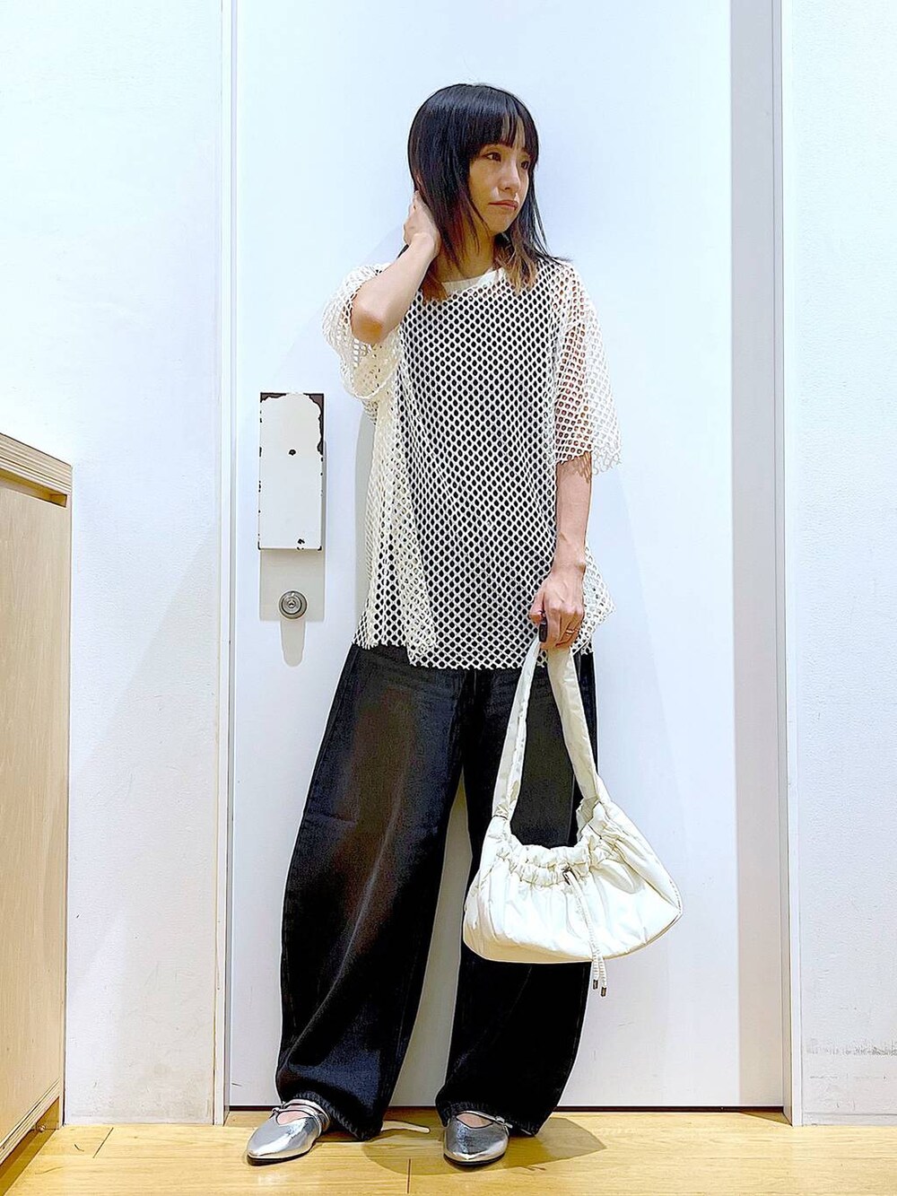ホワイト系のハンドバッグ、ブラック系のニット/セーター、ホワイト系のTシャツ/カットソーを着用したレディースの夏コーディネートの2枚目の写真