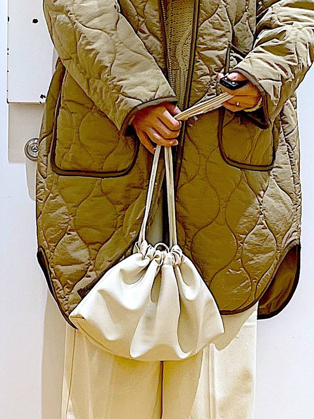 グリーン系のナイロンジャケット、ベージュ系のショルダーバッグ、ブラック系のブーツを着用したレディースの冬コーディネートの9枚目の写真