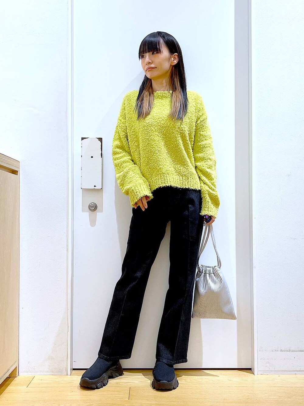 グリーン系のニット/セーター、グレー系のデニムパンツ、シルバー系のショルダーバッグを着用したレディースの冬コーディネートの2枚目の写真