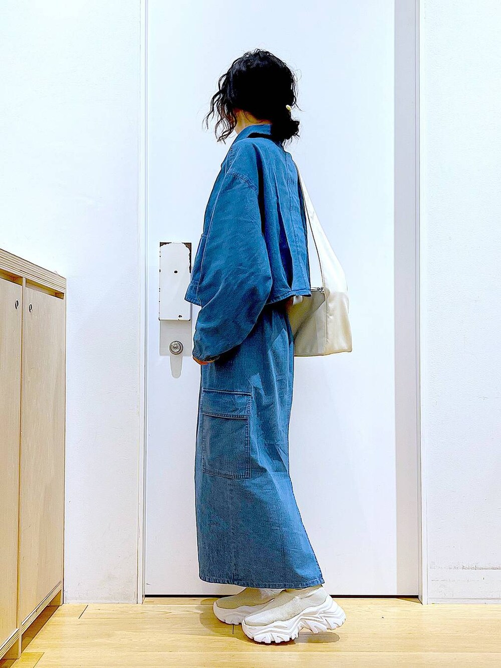 ブルー系のデニムスカート、ブルー系のデニムジャケット、ホワイト系のショルダーバッグを着用したレディースの春コーディネートの3枚目の写真