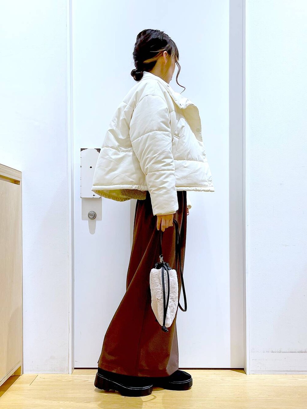 ベージュ系のショルダーバッグ、ブラック系のブーツ、ベージュ系のナイロンジャケットを着用したレディースの冬コーディネートの4枚目の写真