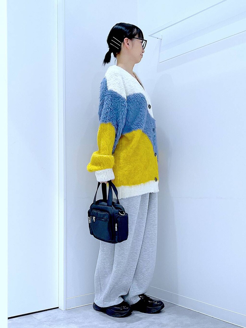 ブラック系のショルダーバッグ、ブラック系のローファー、イエロー系のカーディガン/ボレロを着用したレディースの秋コーディネートの4枚目の写真