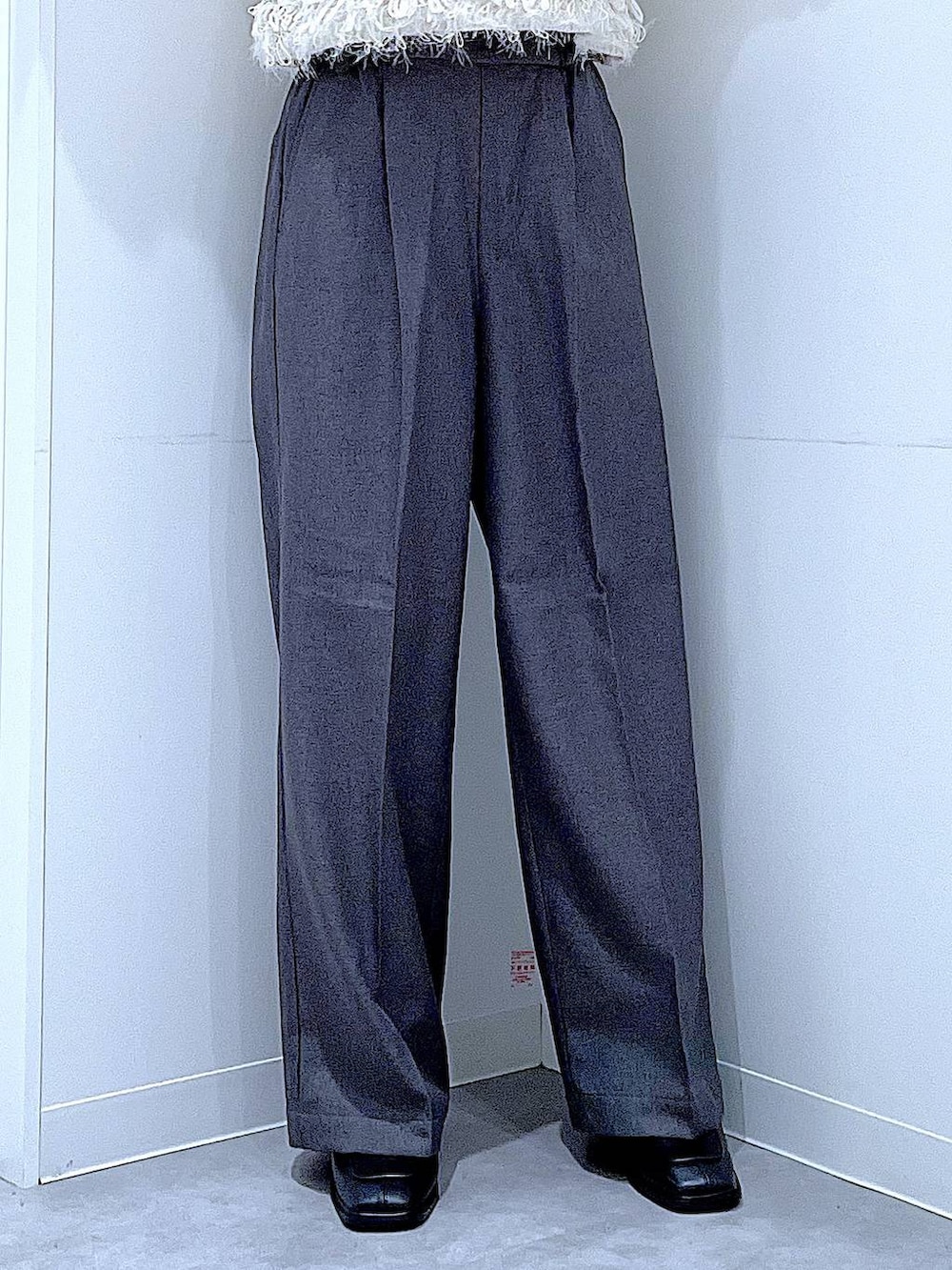 ブラック系のブーツ、グレー系のスラックス、ホワイト系のベストを着用したレディースの冬コーディネートの8枚目の写真