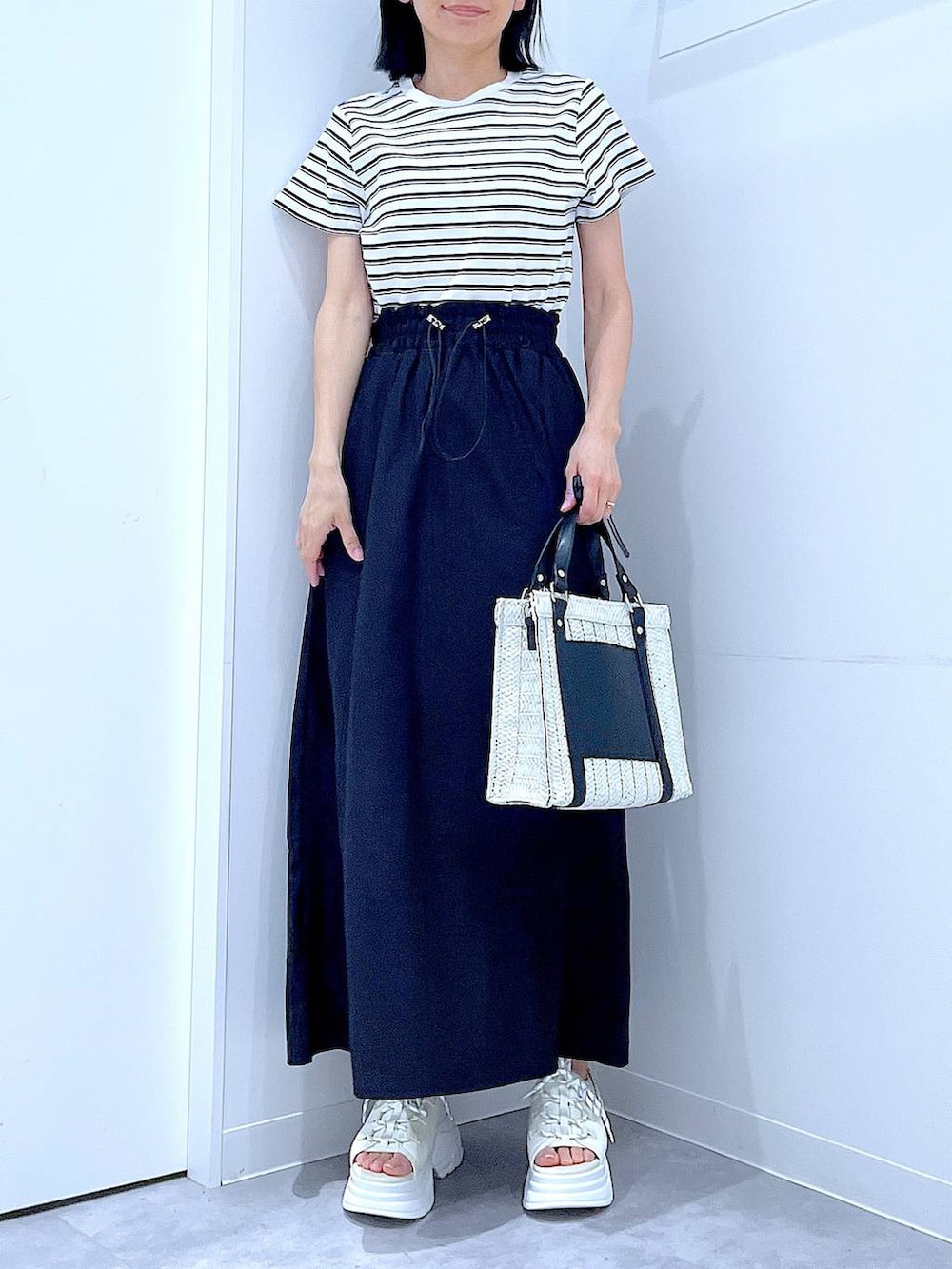ホワイト系のショルダーバッグ、ホワイト系のサンダル、ベージュ系のTシャツ/カットソーを着用したレディースの夏コーディネートの6枚目の写真