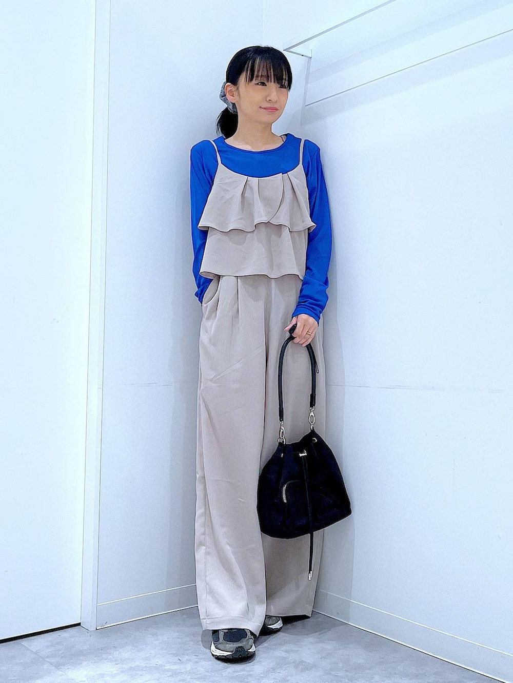 ベージュ系のサロペット/オーバーオール、ブラック系のショルダーバッグ、グレー系のシュシュを着用したレディースの春コーディネートの2枚目の写真