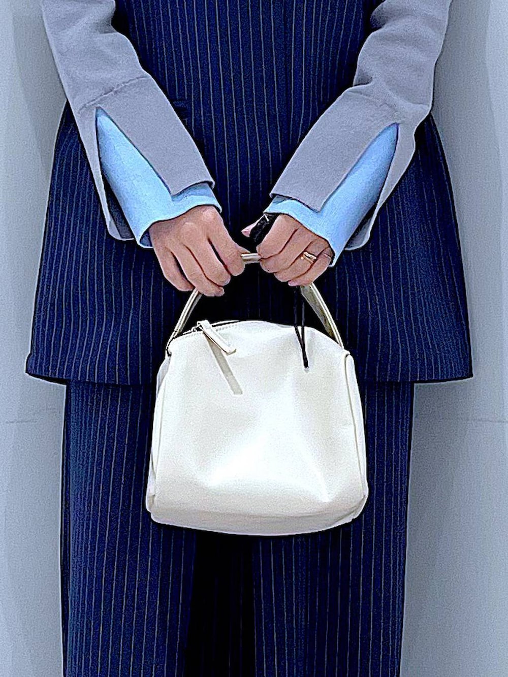 ホワイト系のショルダーバッグ、ブルー系のスラックス、ブルー系のベストを着用したレディースの冬コーディネートの9枚目の写真