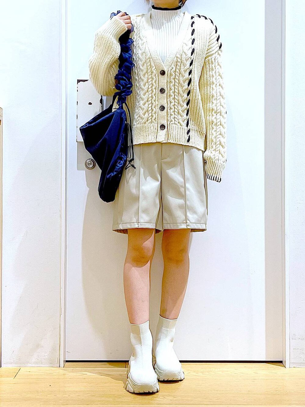 ベージュ系のニット/セーター、ブルー系のショルダーバッグ、ベージュ系のブーツを着用したレディースの冬コーディネートの6枚目の写真