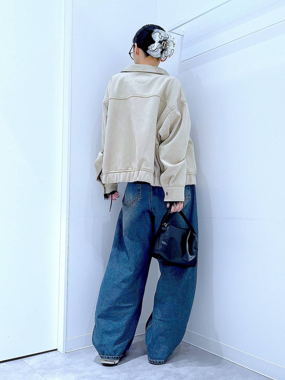 ブルー系のデニムパンツ、ブラック系のショルダーバッグ、ベージュ系のブルゾンを着用したレディースの春コーディネートの5枚目の写真