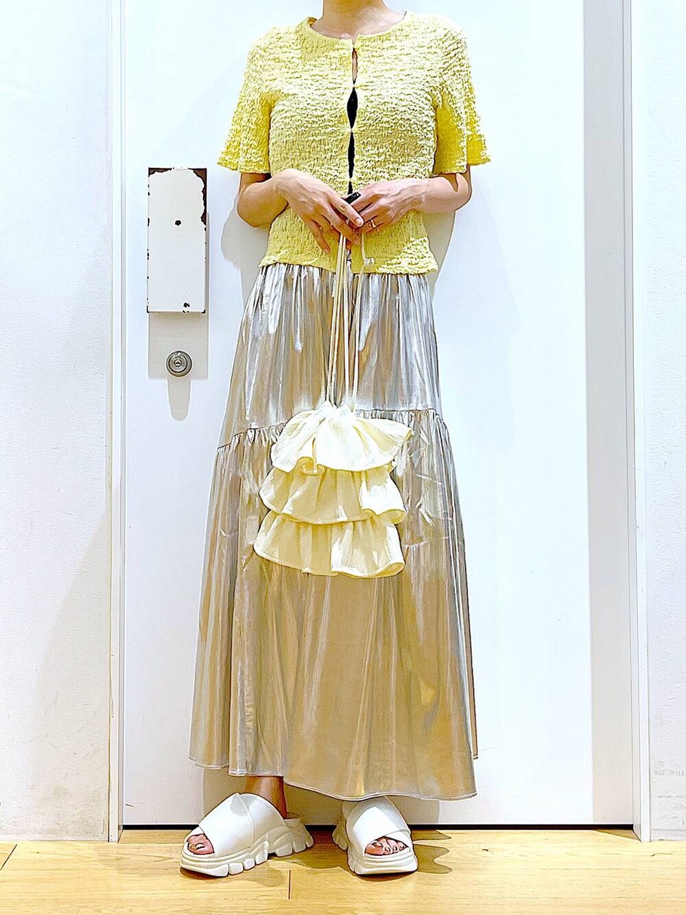 ホワイト系のサンダル、シルバー系のスカート、イエロー系のカーディガン/ボレロを着用したレディースの夏コーディネートの6枚目の写真