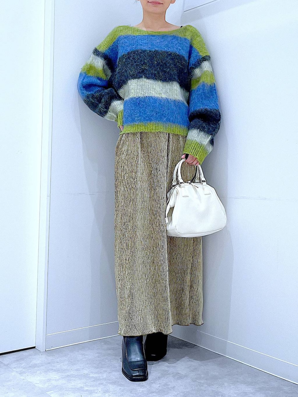 ブラック系のブーツ、ホワイト系のショルダーバッグ、ブルー系のニット/セーターを着用したレディースの冬コーディネートの6枚目の写真