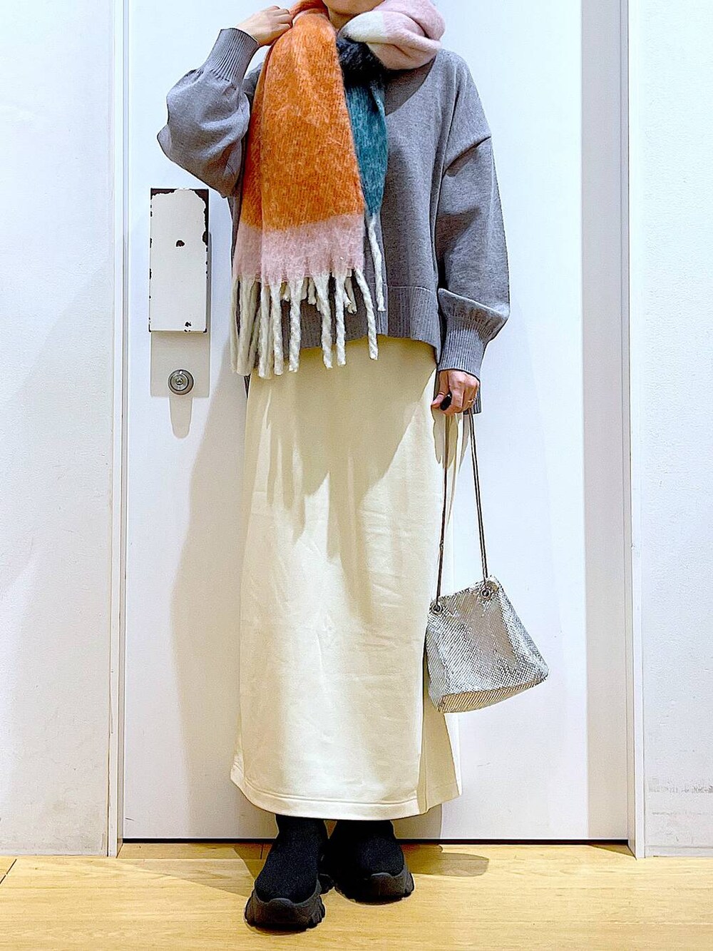 ブラック系のブーツ、ホワイト系のスカート、グレー系のニット/セーターを着用したレディースの冬コーディネートの6枚目の写真