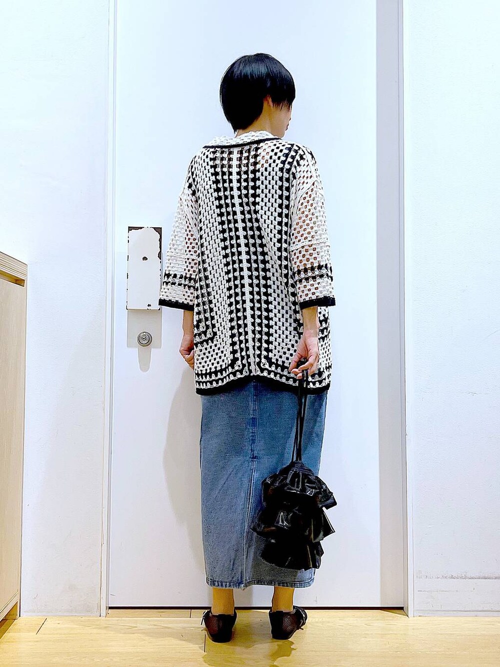 ブラック系のショルダーバッグ、ブラック系のパンプス、ブルー系のジャンパースカートを着用したレディースの春コーディネートの5枚目の写真