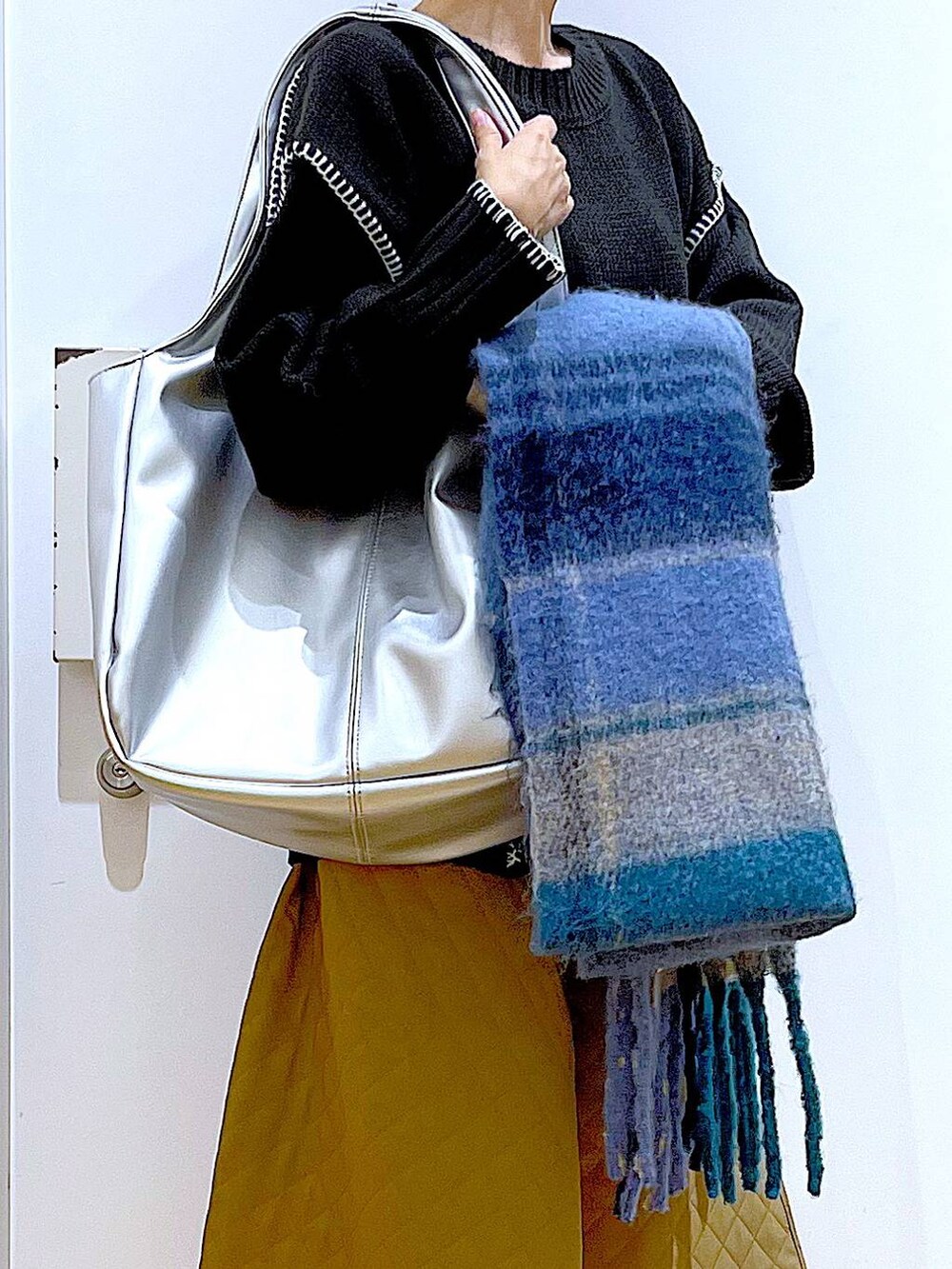 シルバー系のトートバッグ、ベージュ系のブーツ、ブラック系のニット/セーターを着用したレディースの冬コーディネートの9枚目の写真