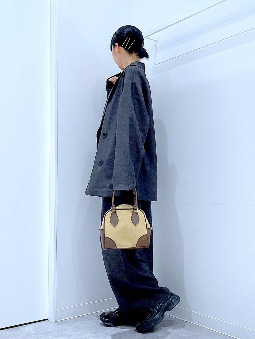 ブラック系のローファー、ベージュ系のハンドバッグ、グレー系のテーラードジャケットを着用したレディースの秋コーディネートの3枚目の写真
