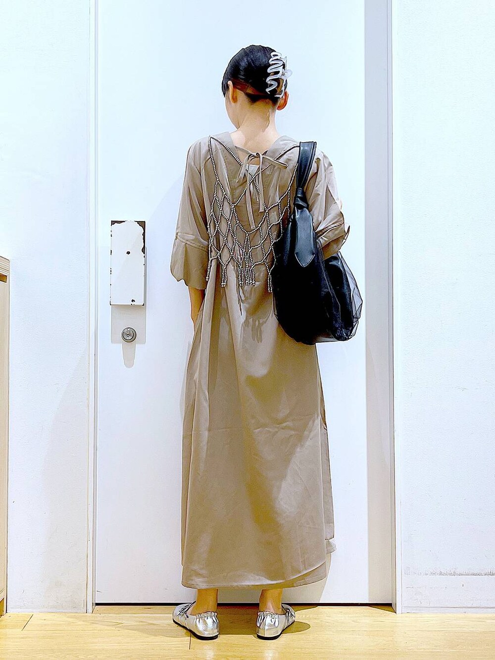 ブラック系のトートバッグ、ベージュ系のワンピース、シルバー系のパンプスを着用したレディースの夏コーディネートの5枚目の写真