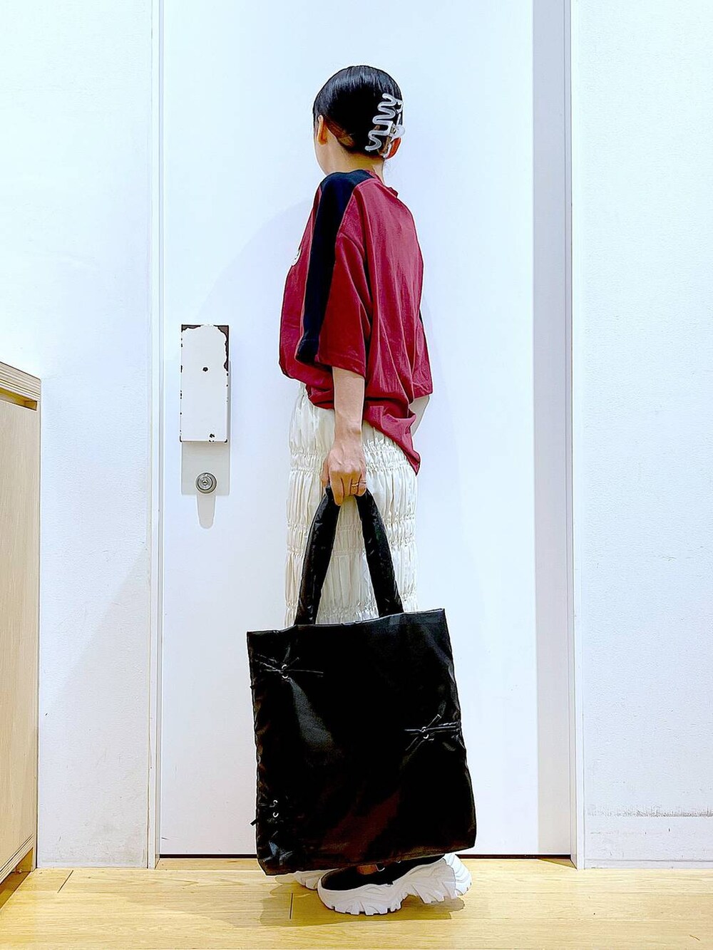 ホワイト系のスカート、ブラック系のスニーカー、ブラック系のトートバッグを着用したレディースの秋コーディネートの3枚目の写真