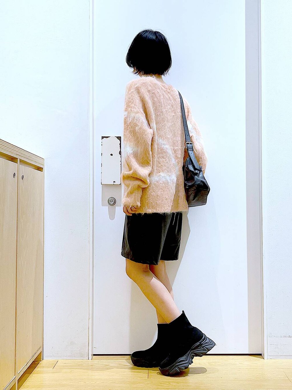 ピンク系のニット/セーター、ブラック系のブーツ、ブラック系のショルダーバッグを着用したレディースの冬コーディネートの3枚目の写真