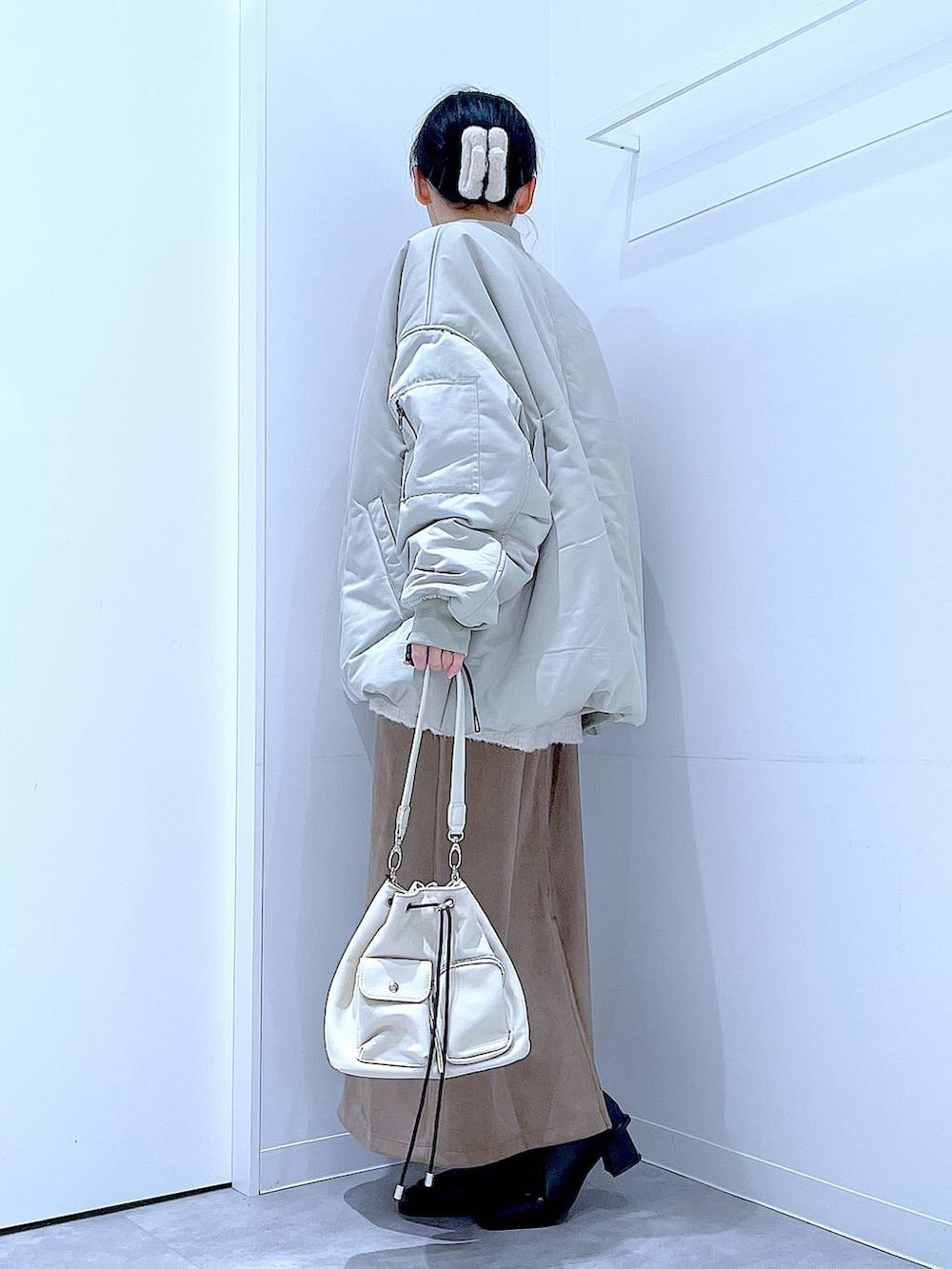 ベージュ系のニット/セーター、ブラック系のブーツ、ブラウン系のスカートを着用したレディースの冬コーディネートの3枚目の写真