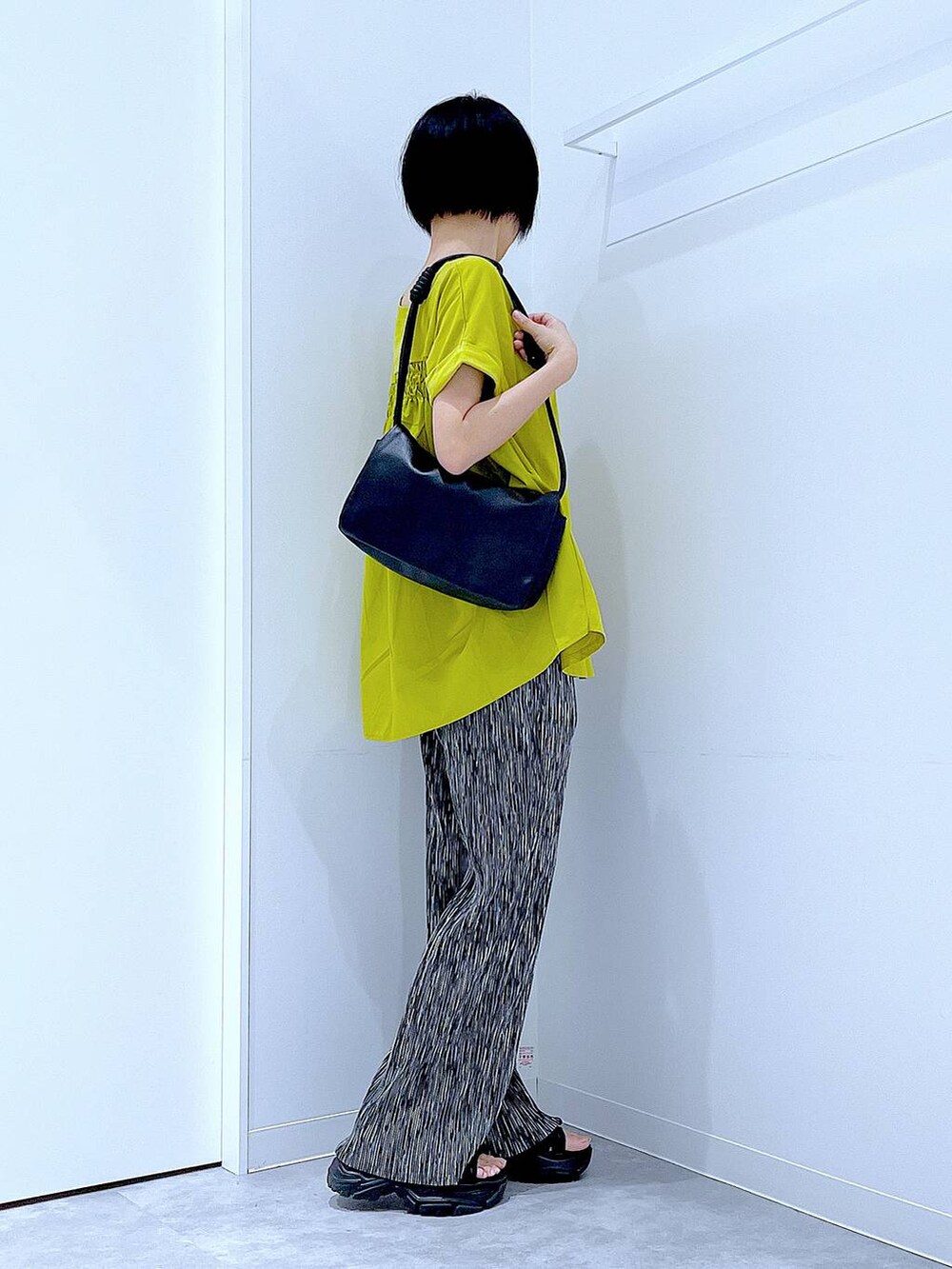 ブラック系のスニーカー、ブラック系のショルダーバッグ、グリーン系のTシャツ/カットソーを着用したレディースの夏コーディネートの4枚目の写真