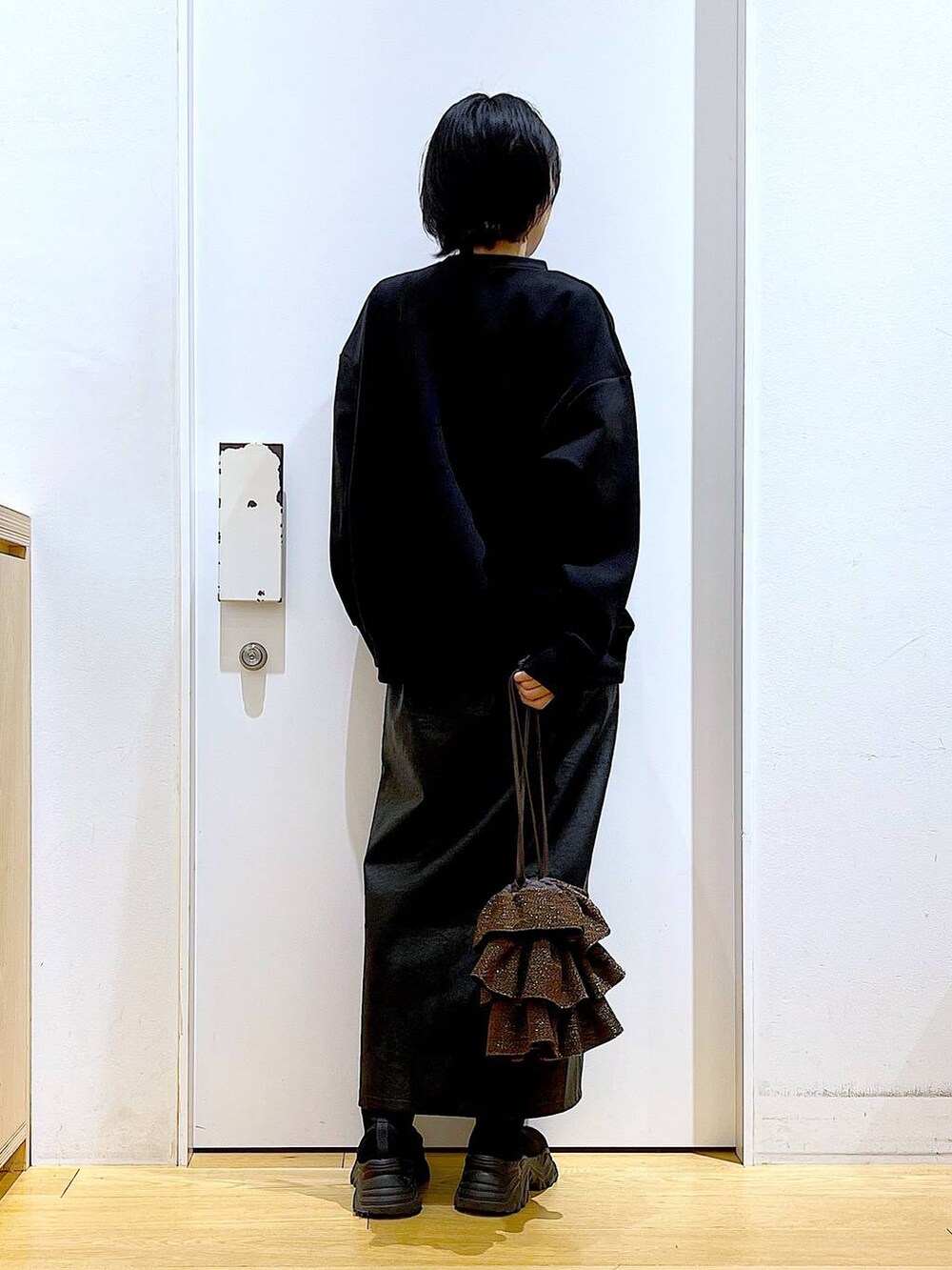 ブラック系のスカート、ブラック系のブーツ、ブラウン系のショルダーバッグを着用したレディースの冬コーディネートの5枚目の写真