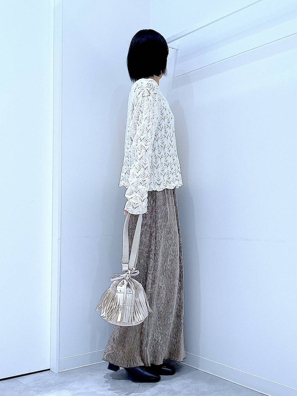 ブラック系のブーツ、ホワイト系のショルダーバッグ、ベージュ系のカーディガン/ボレロを着用したレディースの冬コーディネートの4枚目の写真