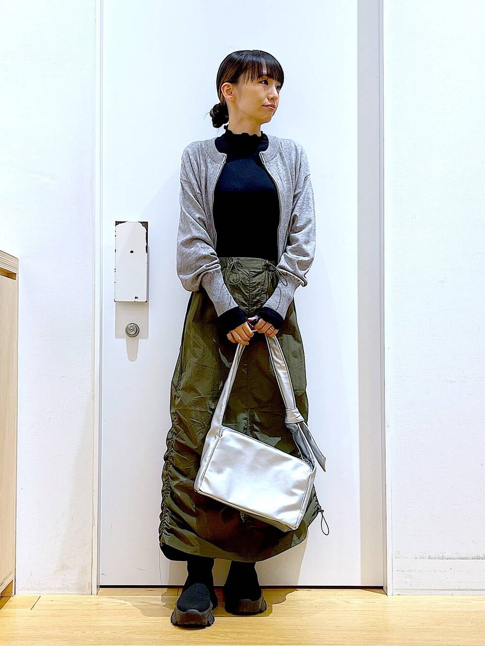 ブラック系のTシャツ/カットソー、グレー系のカーディガン/ボレロ、ブラック系のブーツを着用したレディースの冬コーディネートの2枚目の写真