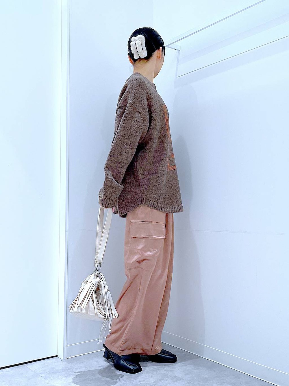 ブラウン系のニット/セーター、ブラック系のブーツ、ホワイト系のショルダーバッグを着用したレディースの冬コーディネートの4枚目の写真