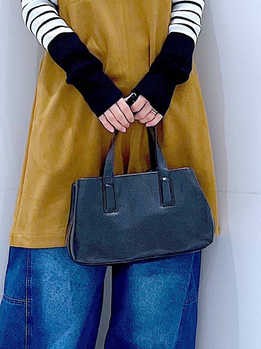 ブラック系のボストンバッグ、ホワイト系のニット/セーター、イエロー系のワンピースを着用したレディースの春コーディネートの9枚目の写真