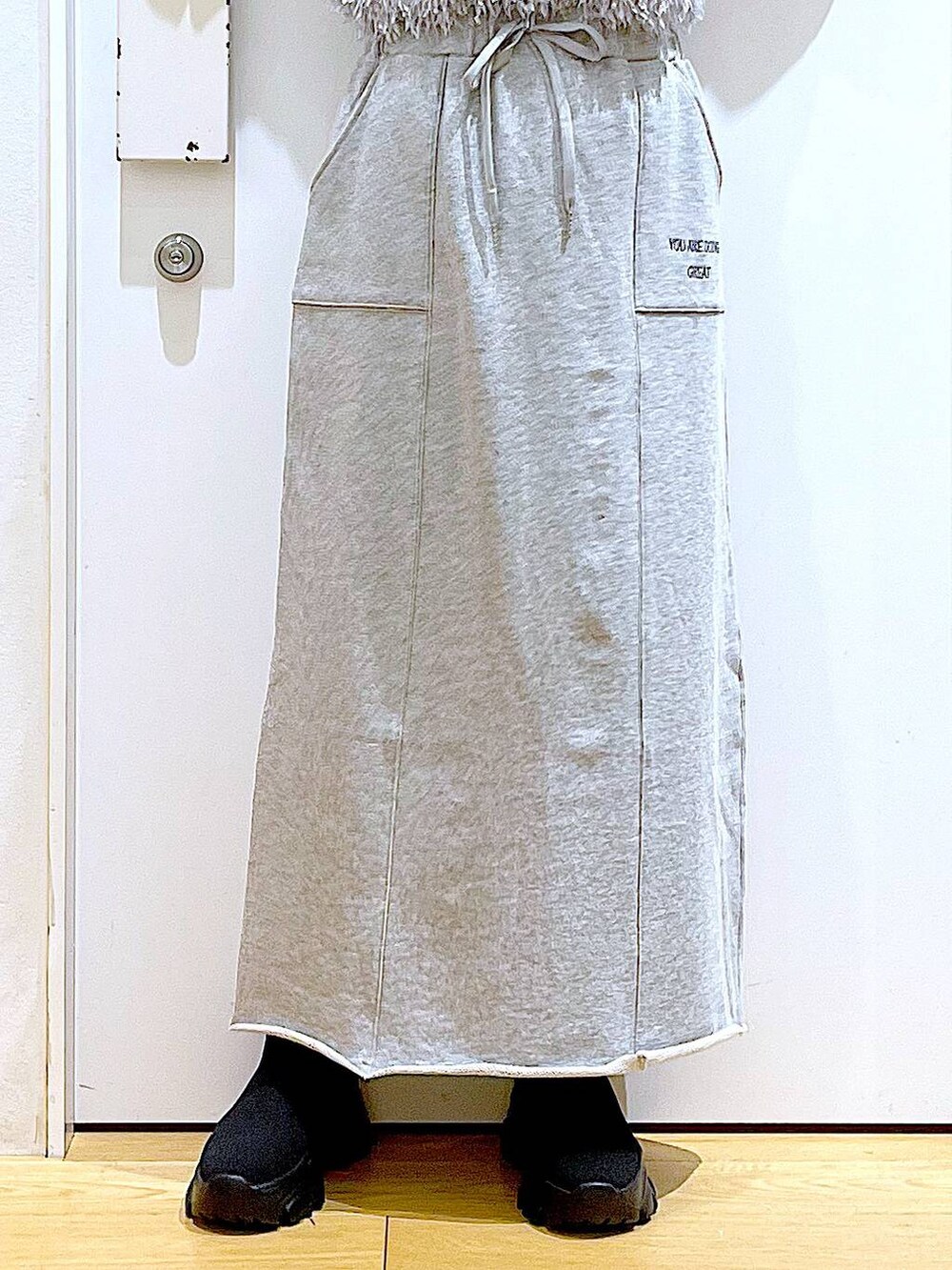 ブラック系のブーツ、ブラック系のTシャツ/カットソー、グレー系のスカートを着用したレディースの春コーディネートの8枚目の写真