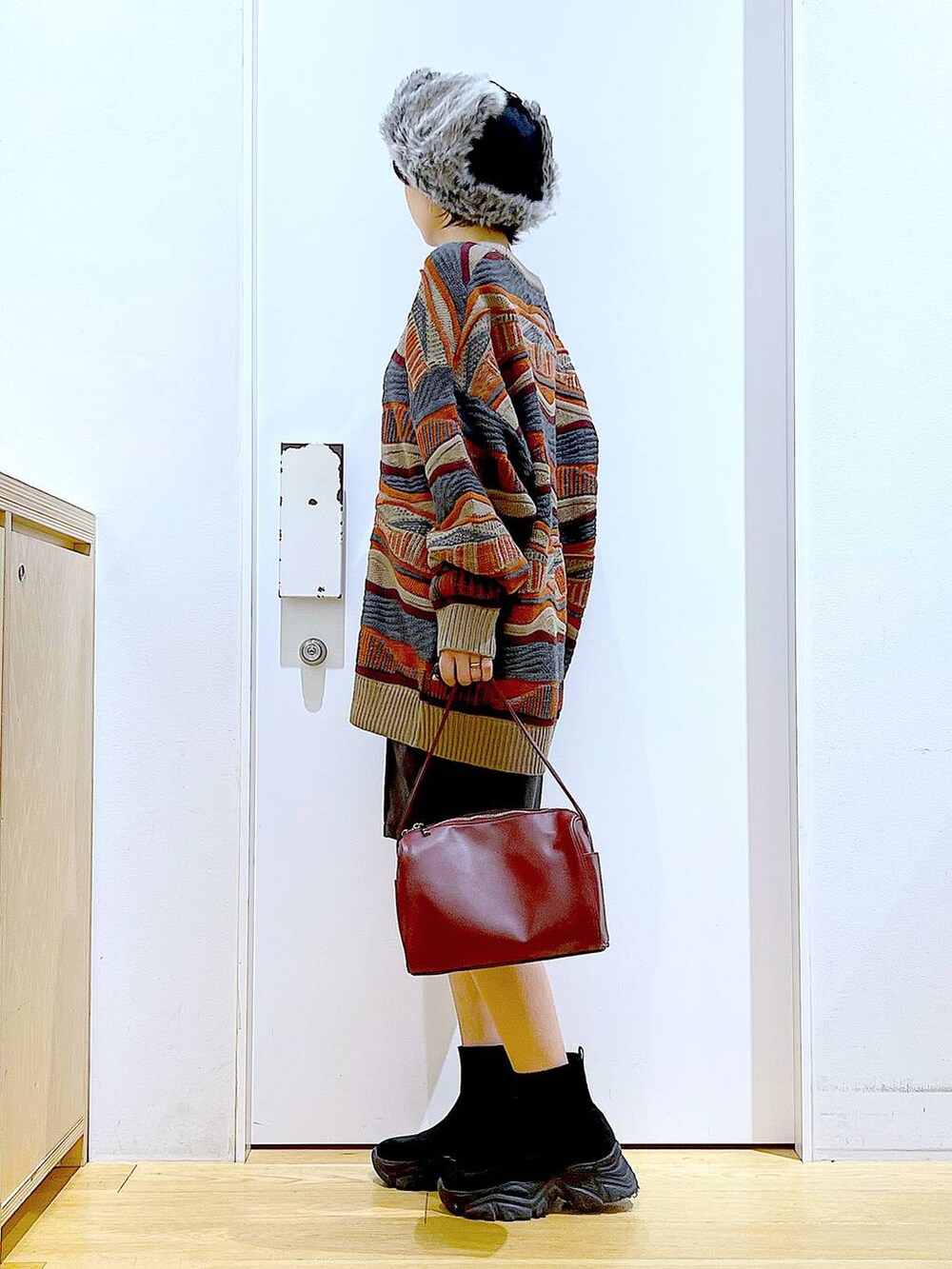 レッド系のショルダーバッグ、ブラック系のブーツ、ブラック系のその他パンツを着用したレディースの冬コーディネートの3枚目の写真