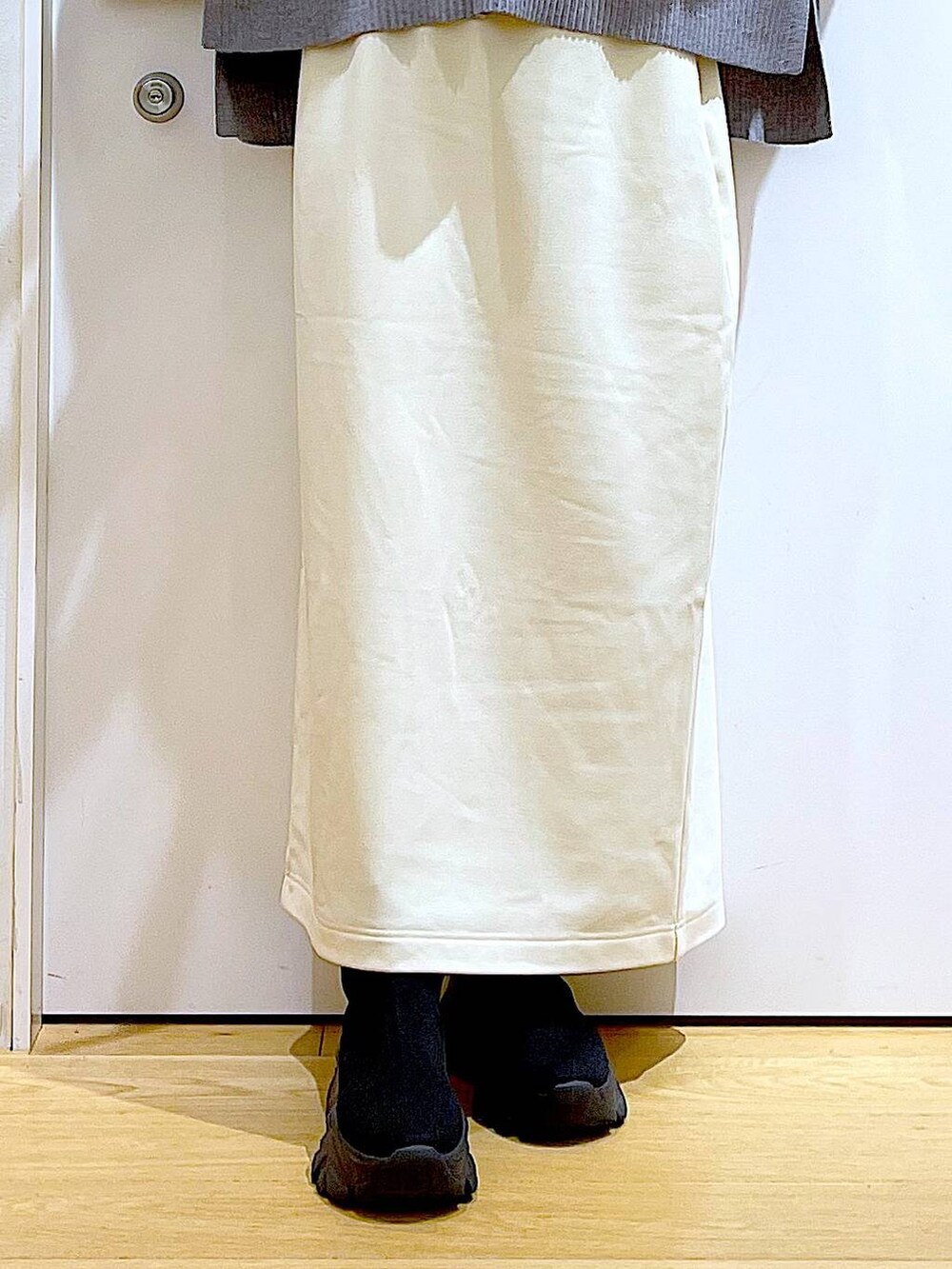 ブラック系のブーツ、ホワイト系のスカート、グレー系のニット/セーターを着用したレディースの冬コーディネートの8枚目の写真