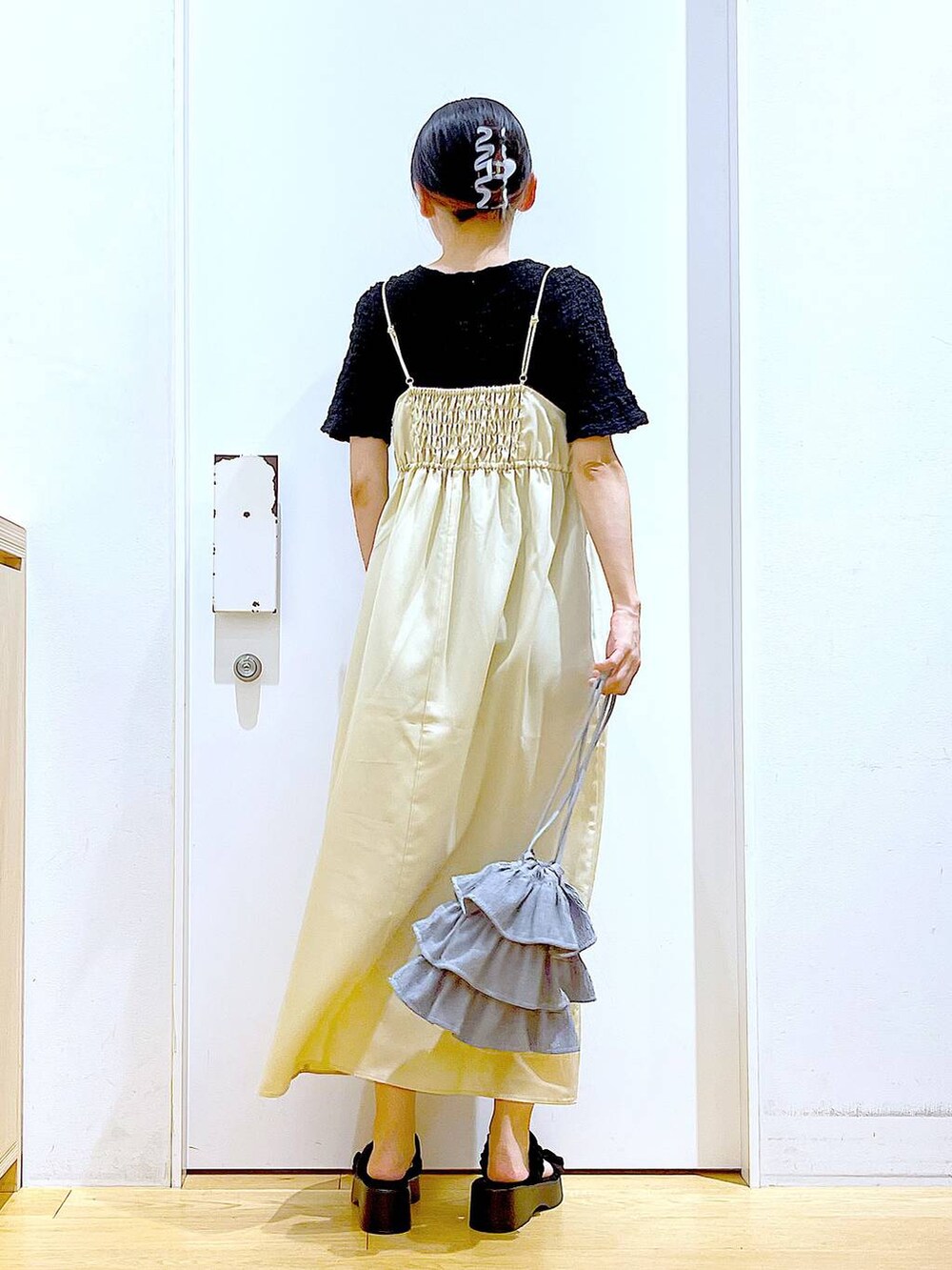 ブラック系のサンダル、イエロー系のワンピース、ブラック系のカーディガン/ボレロを着用したレディースの夏コーディネートの5枚目の写真