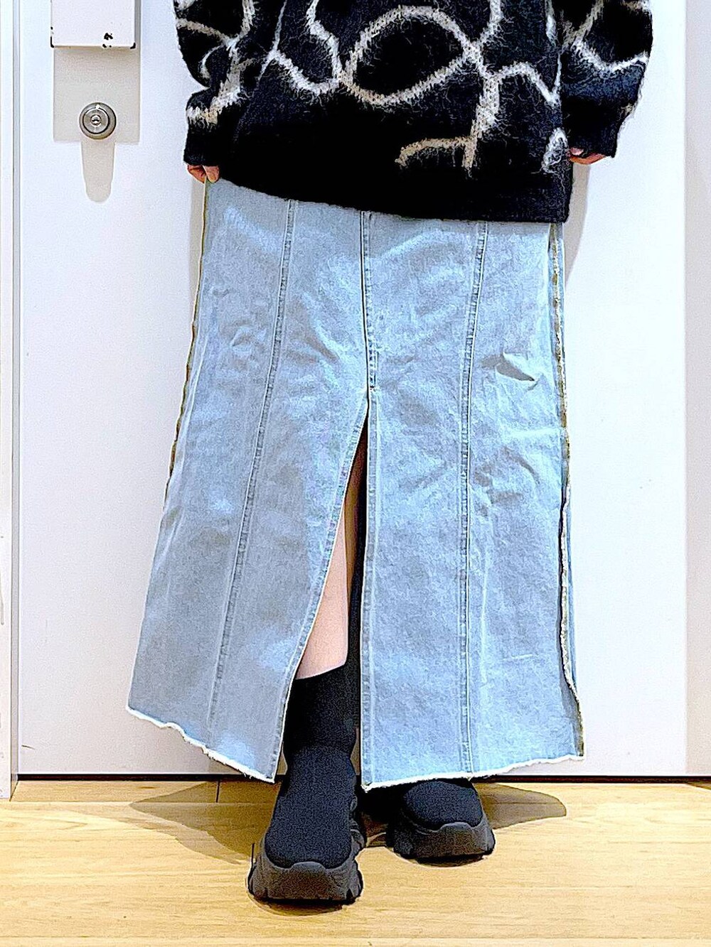 ブルー系のデニムスカート、ブラック系のブーツ、ブラック系のショルダーバッグを着用したレディースの冬コーディネートの8枚目の写真