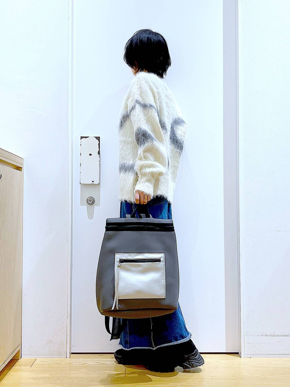 ホワイト系のニット/セーター、グレー系のバックパック/リュック、ブルー系のデニムスカートを着用したレディースの冬コーディネートの3枚目の写真