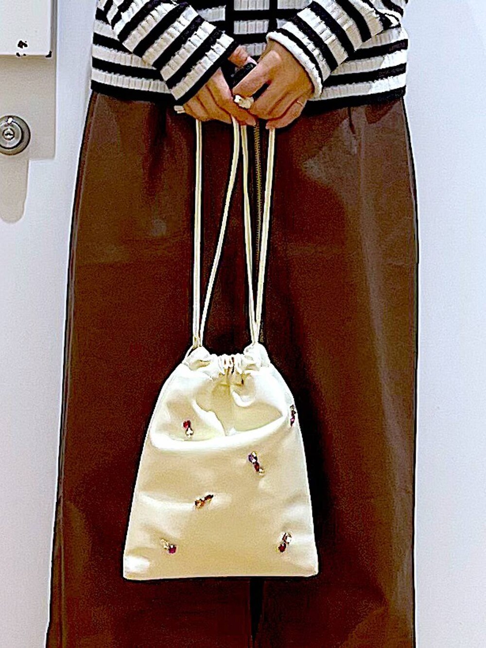 ブラウン系のスカート、ホワイト系のショルダーバッグ、ブラック系のブーツを着用したレディースの秋コーディネートの9枚目の写真