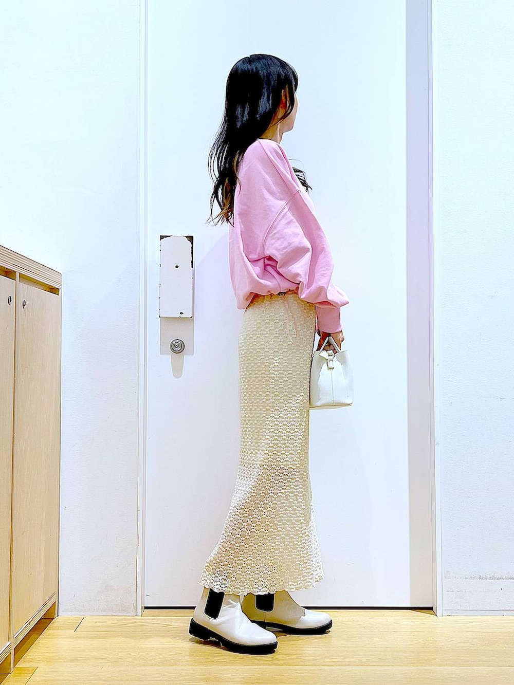 ピンク系のスウェット、ベージュ系のブーツ、ホワイト系のショルダーバッグを着用したレディースの春コーディネートの4枚目の写真