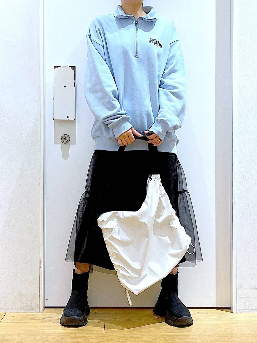 ブルー系のスウェット、ブラック系のブーツ、ホワイト系のショルダーバッグを着用したレディースの春コーディネートの6枚目の写真