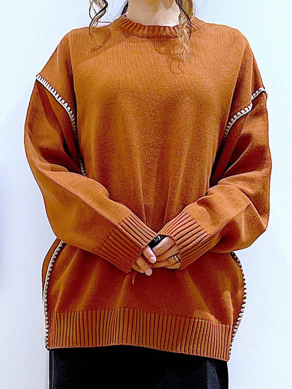 グレー系のスカート、オレンジ系のニット/セーター、ブラウン系のクラッチバッグを着用したレディースの冬コーディネートの7枚目の写真