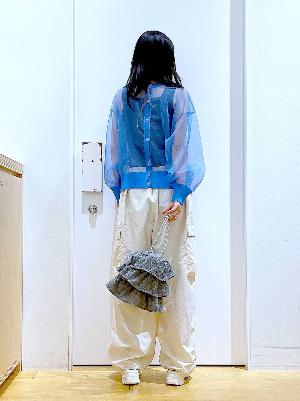 シルバー系のショルダーバッグ、ホワイト系のカーゴパンツ、ブラック系のニット/セーターを着用したレディースの夏コーディネートの5枚目の写真