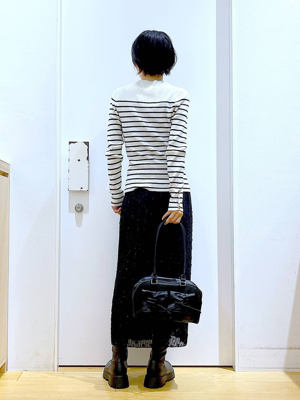 ホワイト系のニット/セーター、ブラック系のハンドバッグ、ブラック系のブーツを着用したレディースの秋コーディネートの5枚目の写真