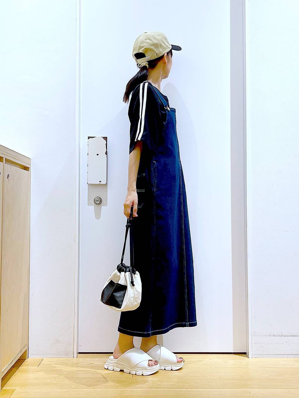 ブルー系のジャンパースカート、ホワイト系のショルダーバッグ、ホワイト系のサンダルを着用したレディースの夏コーディネートの4枚目の写真