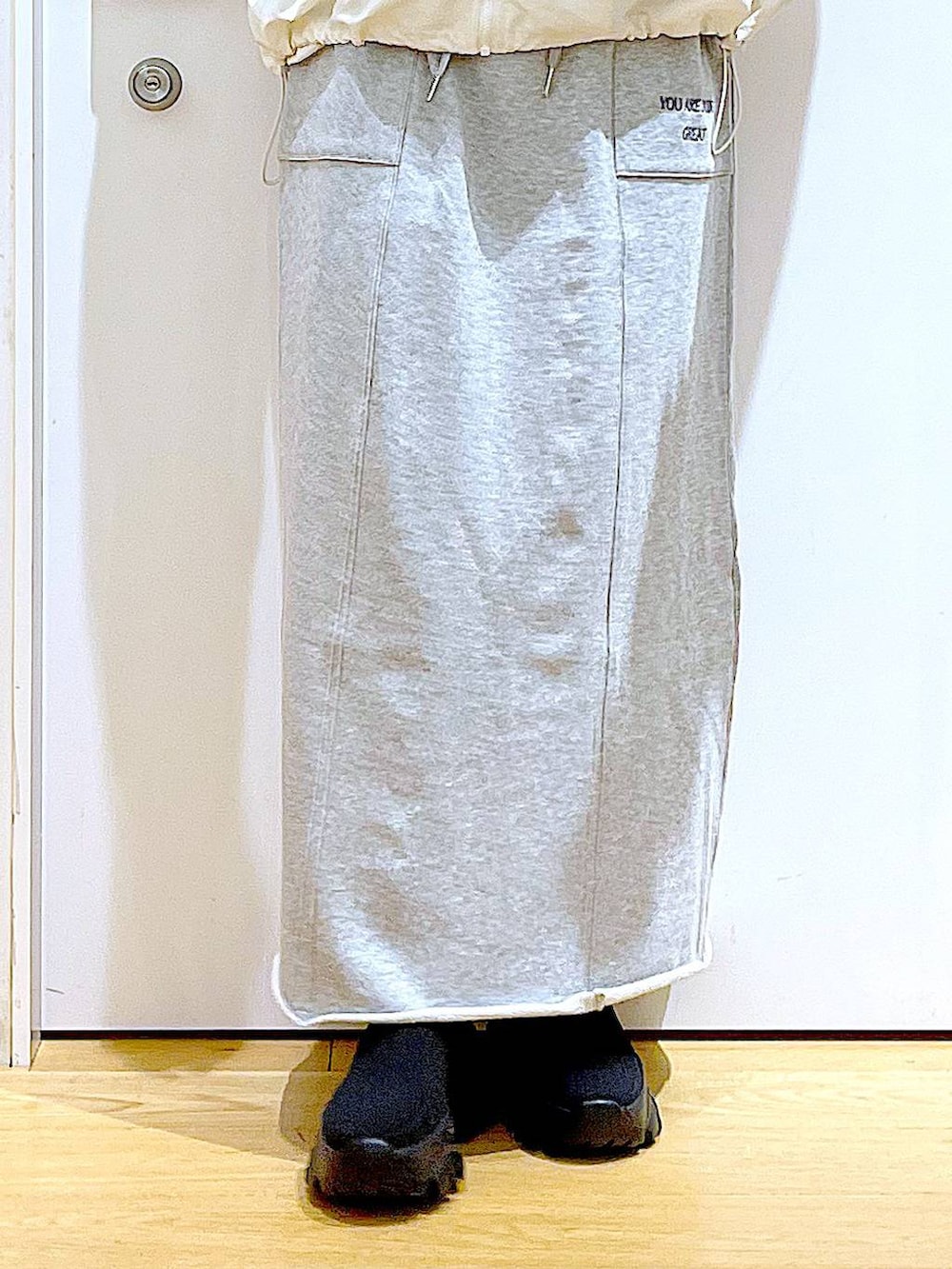 ブラック系のブーツ、ブラック系のショルダーバッグ、グレー系のスカートを着用したレディースの春コーディネートの8枚目の写真