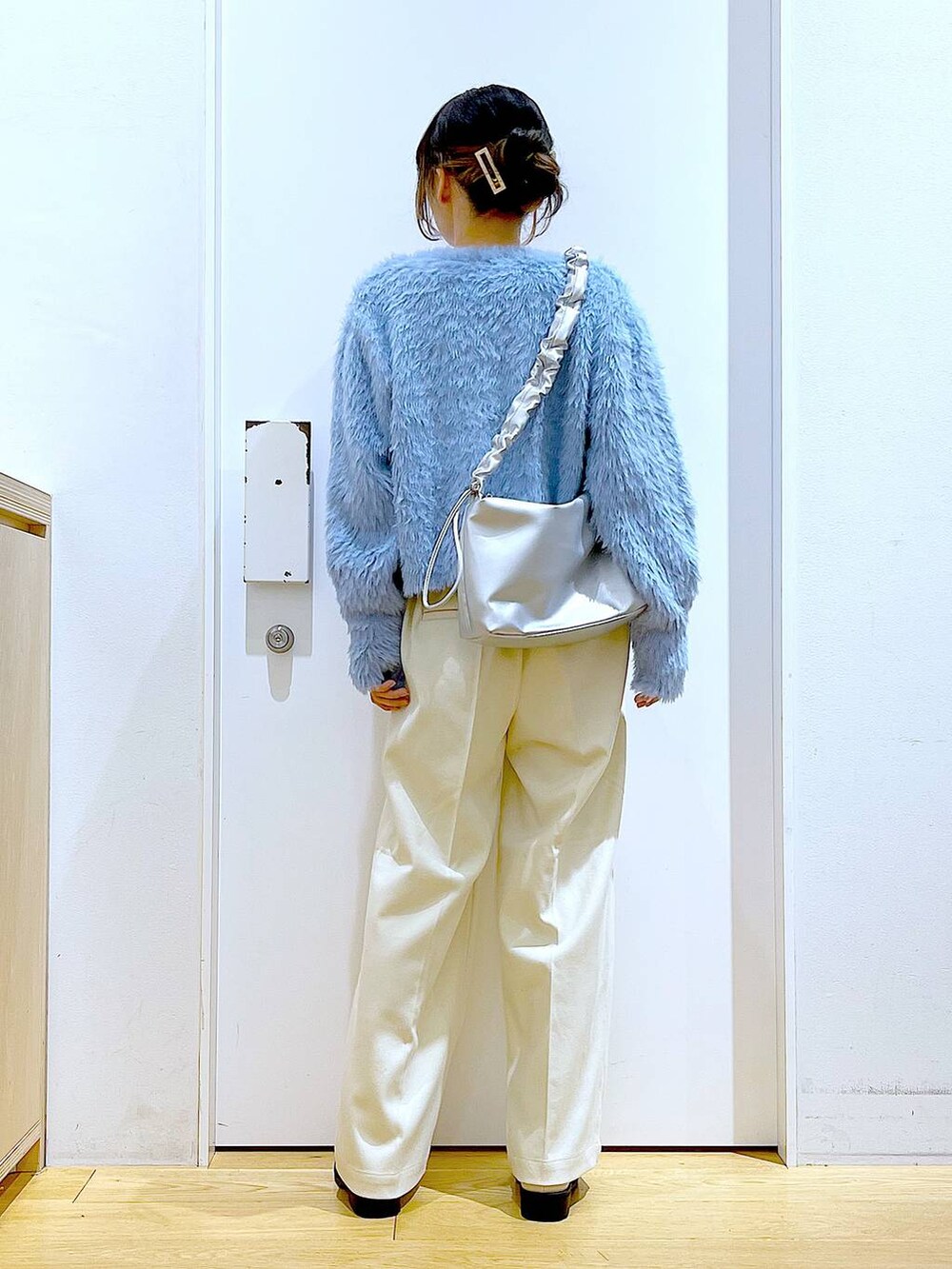 シルバー系のショルダーバッグ、ベージュ系のブーツ、ホワイト系のニット/セーターを着用したレディースの冬コーディネートの5枚目の写真