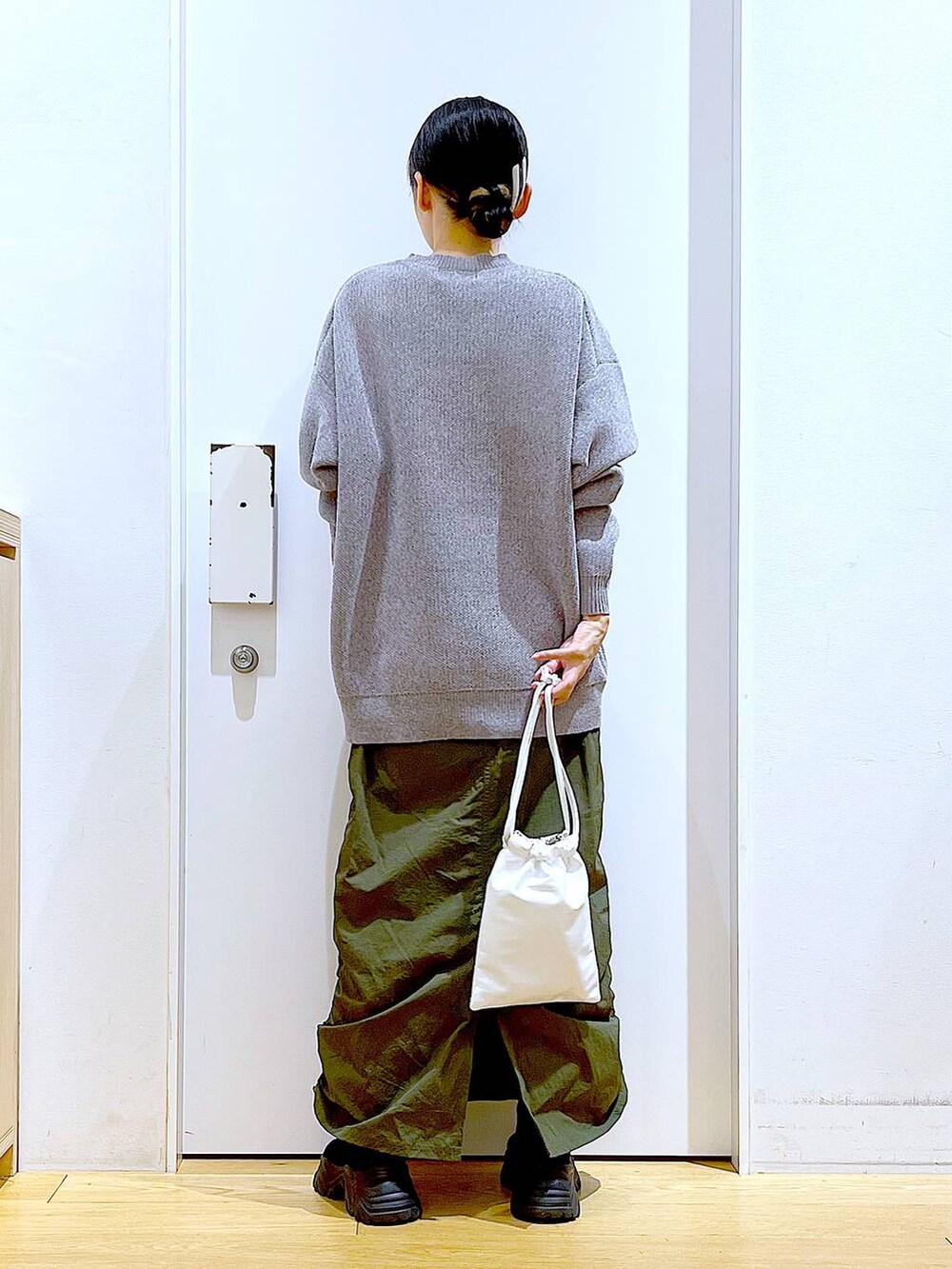 ブラック系のブーツ、グレー系のニット/セーター、グリーン系のスカートを着用したレディースの冬コーディネートの5枚目の写真