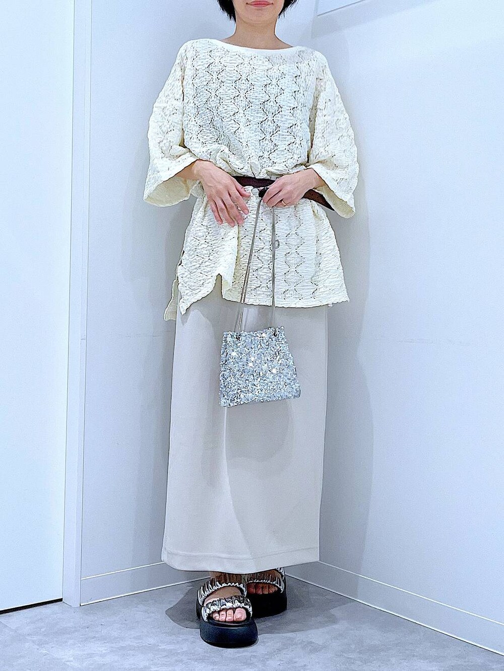 シルバー系のサンダル、ベージュ系のスカート、シルバー系のショルダーバッグを着用したレディースの夏コーディネートの6枚目の写真