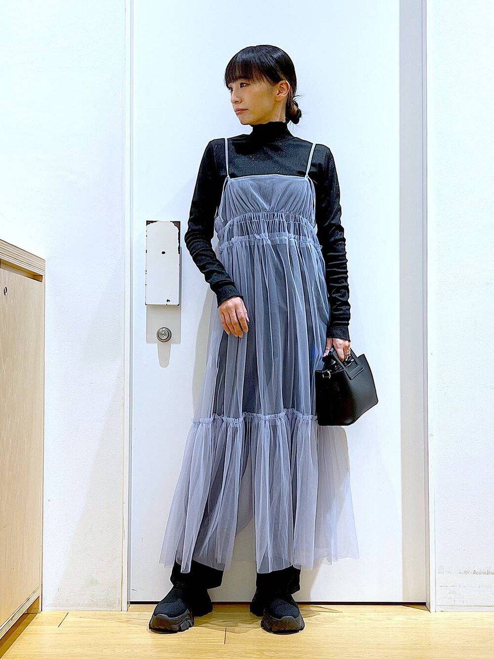 グレー系のデニムパンツ、ブルー系のワンピース、ブラック系のTシャツ/カットソーを着用したレディースの春コーディネートの2枚目の写真