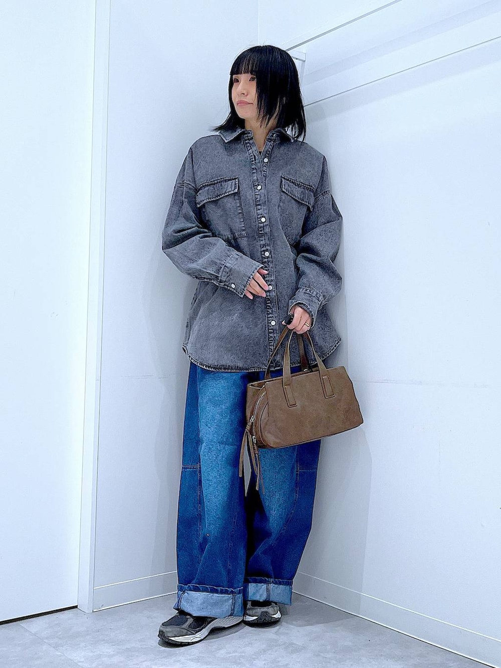 ブラウン系のボストンバッグ、ブルー系のデニムパンツ、ブラック系のシャツ/ブラウスを着用したレディースの冬コーディネートの2枚目の写真