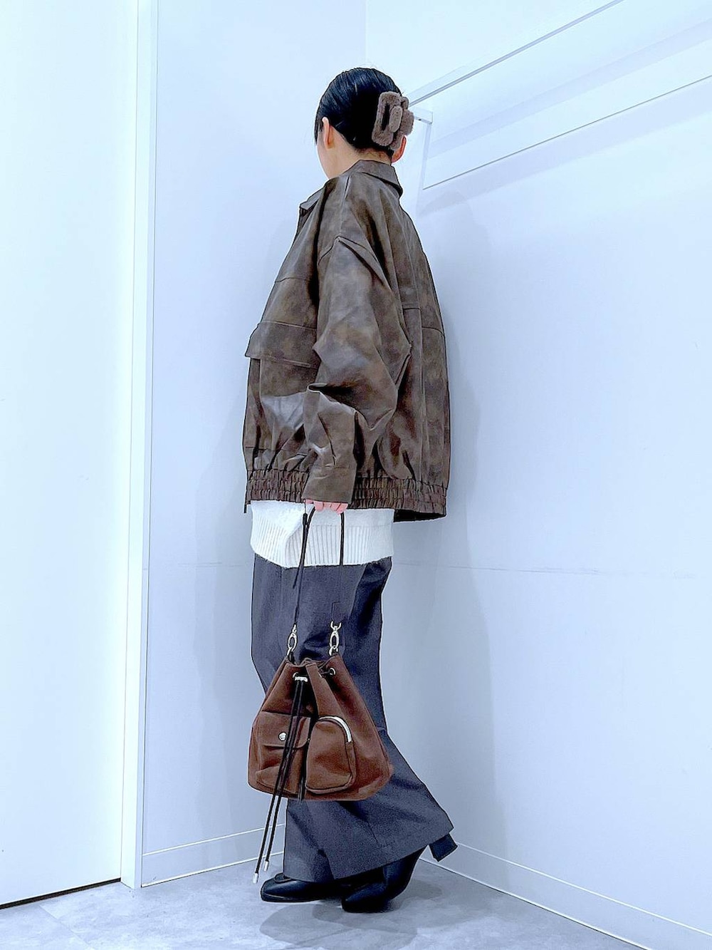 ブラウン系のブルゾン、ブラウン系のショルダーバッグ、ブラック系のブーツを着用したレディースの冬コーディネートの3枚目の写真