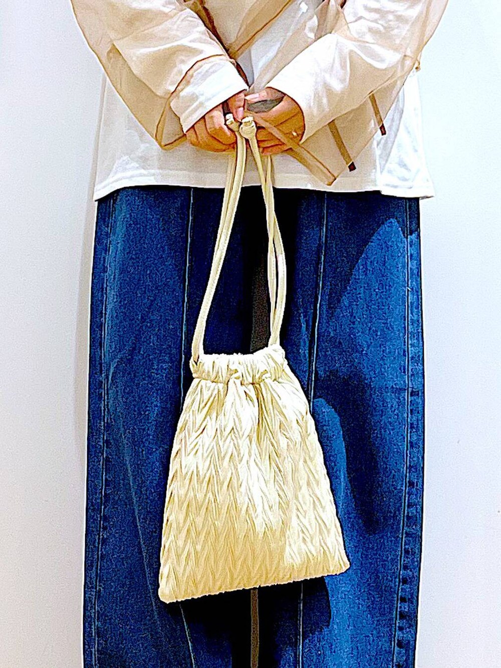 ホワイト系のショルダーバッグ、ホワイト系のパンプス、ブルー系のデニムパンツを着用したレディースの秋コーディネートの9枚目の写真