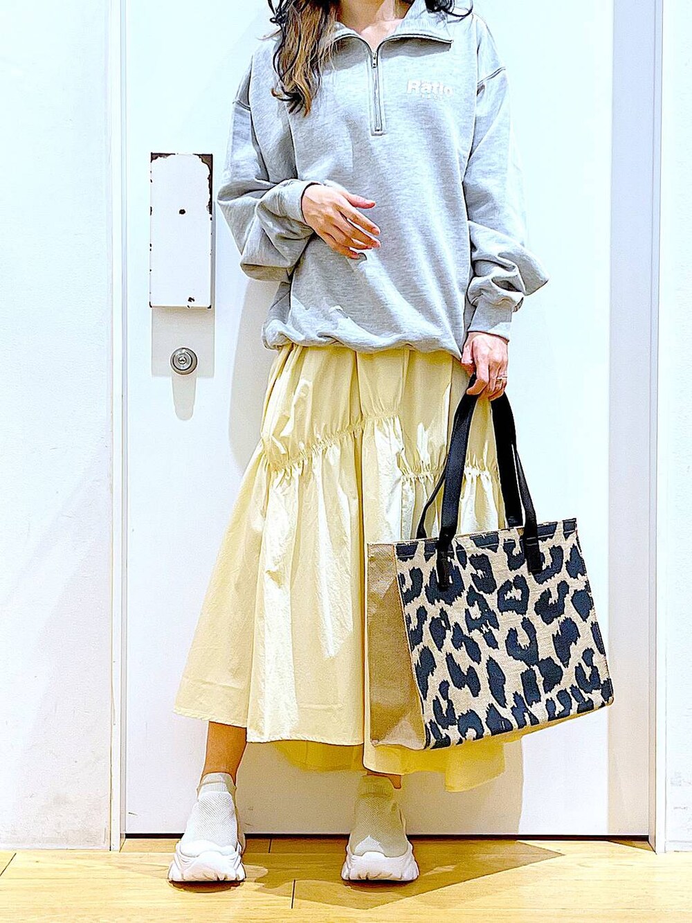 グレー系のスウェット、ベージュ系のスニーカー、イエロー系のスカートを着用したレディースの春コーディネートの6枚目の写真